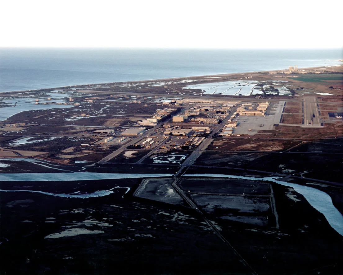 aerial view of a coastal airfield with runways beside a lagoon at dawn