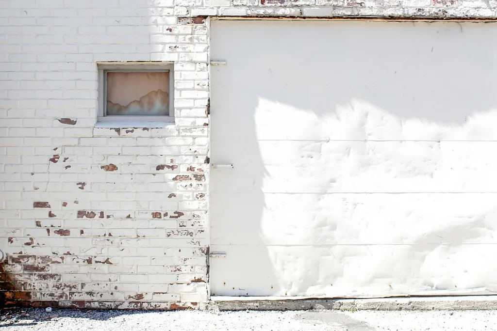 a white garage door set into a painted brick wall